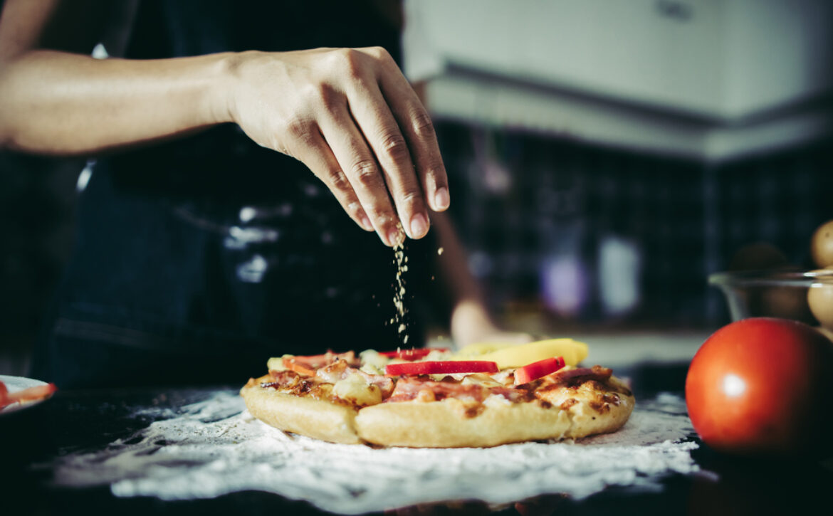 Close up of woman hand putting oregano over tomato and mozzarell